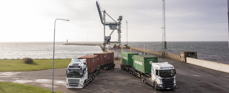 Högkapacitetsfordon lastade med containrar vid havet