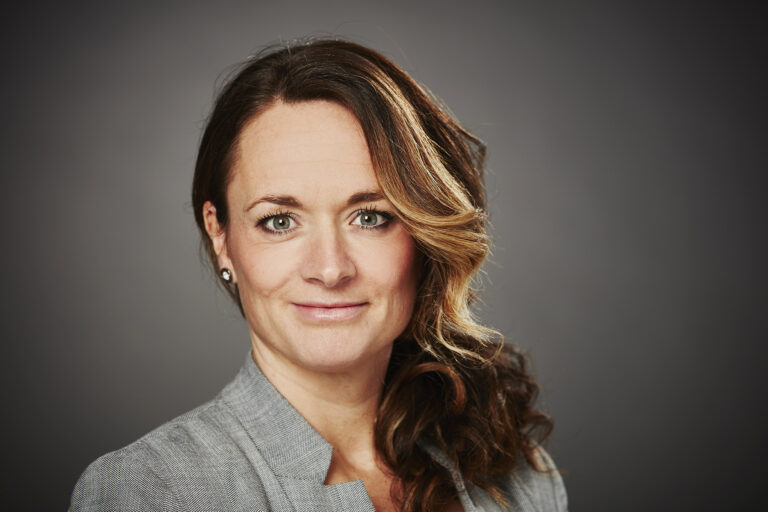 Kvinna med mörkt hår i grå skjorta. Porträttbild